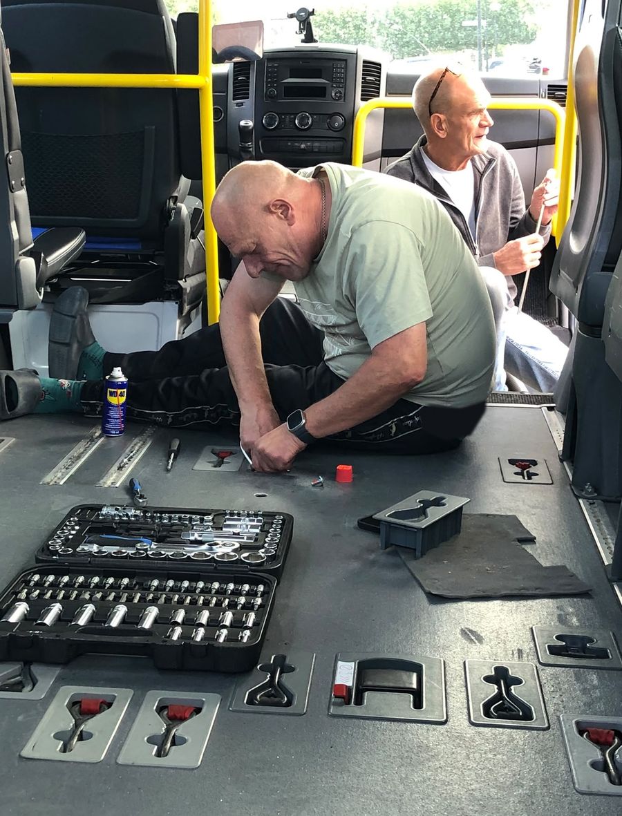 Gerard van Eck werkt met eigen gereedschap op de vloer van een rolstoelbus